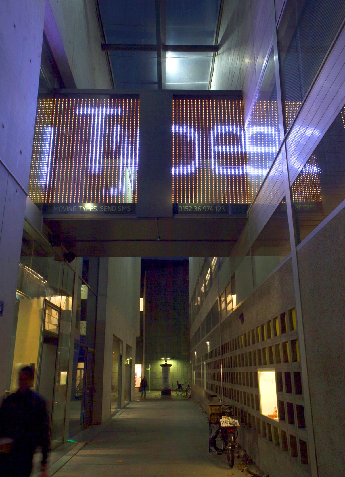 Looking up through the passage to the glass bridge, where the word Types glows in white letters on the LED bars