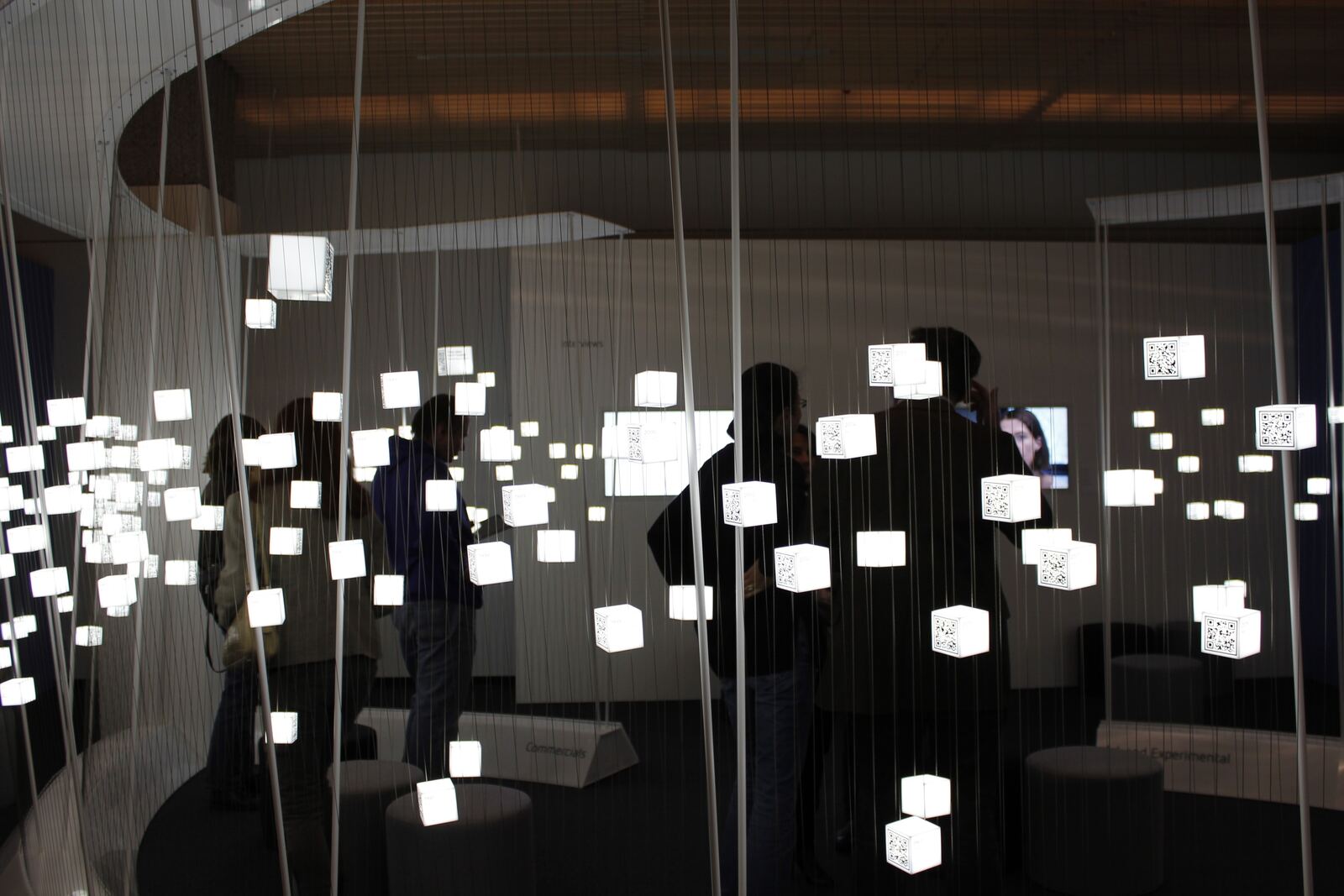 Backlit QR cubes glowing in the dark among the wires of the media lounge