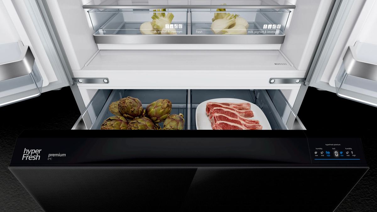 The open fresh drawer of a black refrigerator with vegetables and meat, its own small display on the front edge