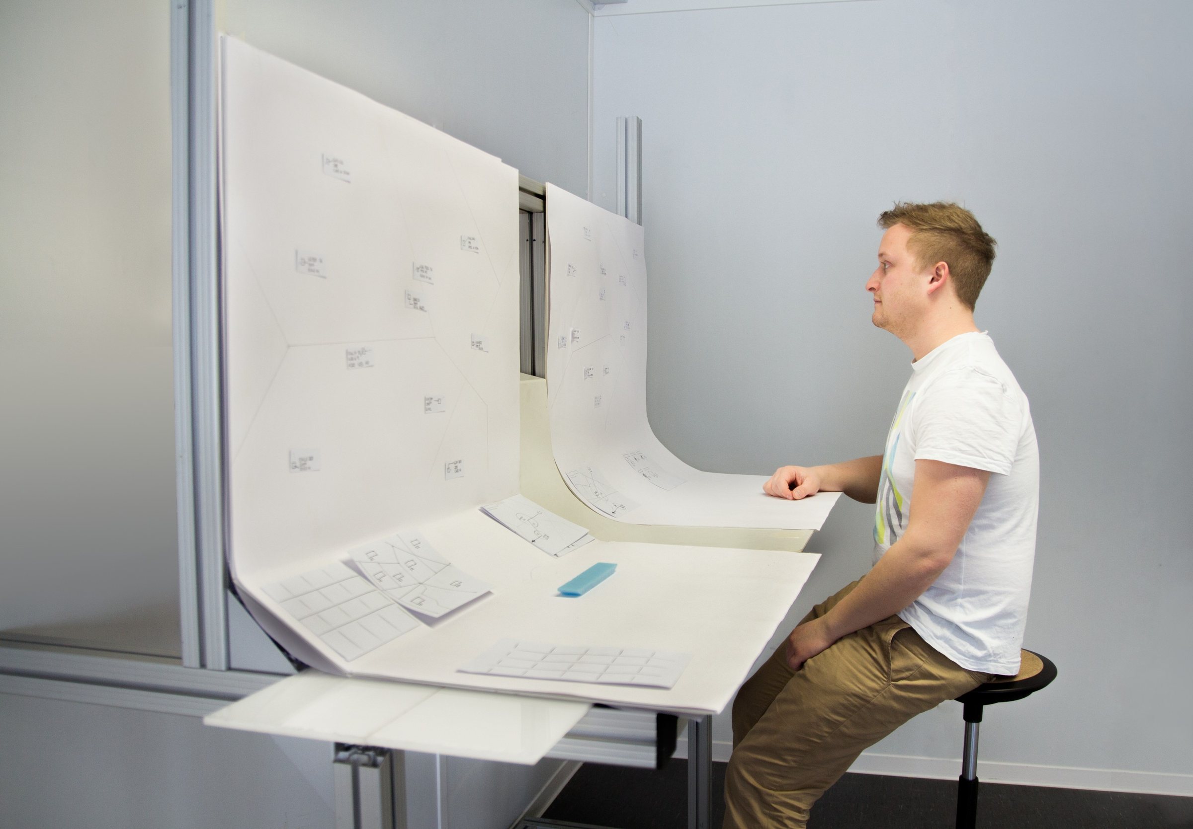 Team member evaluating a curved paper screen mock-up at full scale